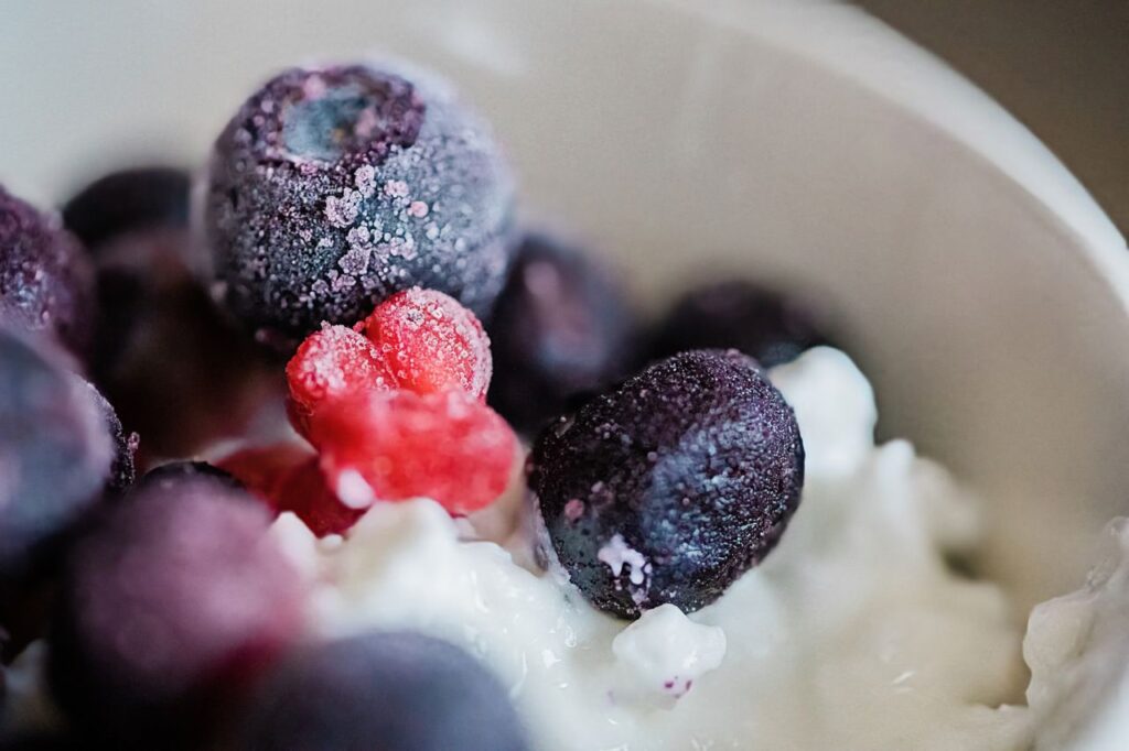 Bevroren fruit in de blender: bevroren bessen met yoghurt in een kom