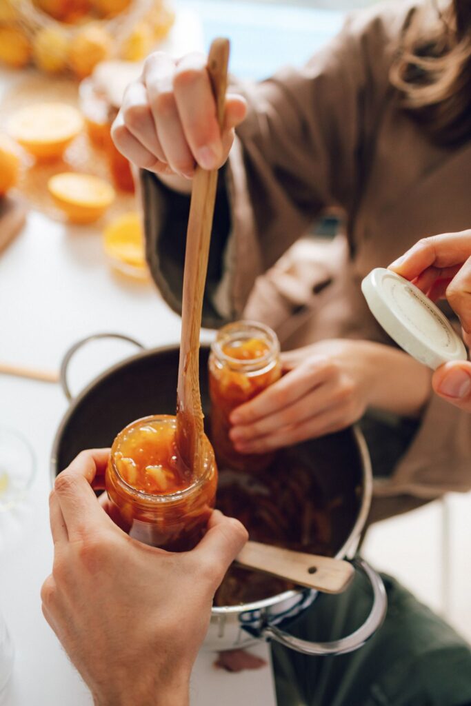 Jam maken met gelatineblaadjes: jampotten vullen met een houten lepel