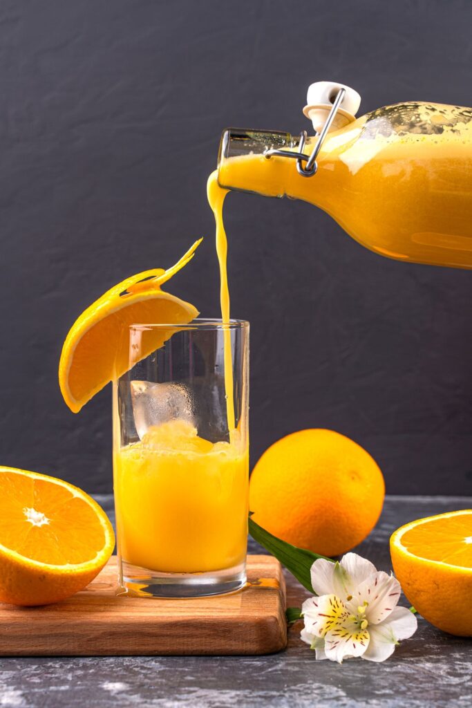 Sinaasappelsap zelf maken: verse sinaasappelsap uit een fles in een glas