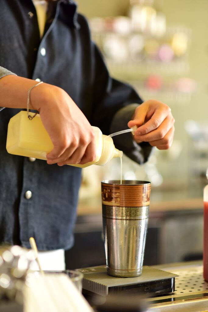 Vanillesiroop gebruiken: siroop uit een knijpfles in een shaker gieten